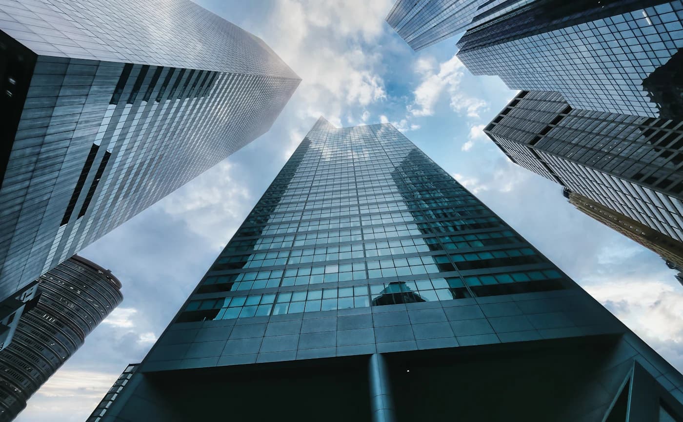 Looking up at glass office towers against a cloudy sky